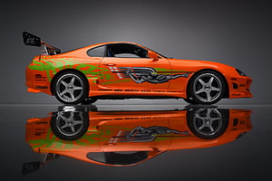 Orange Toyota Supra with Green Camo Wrap and Custom Graphics in Studio Setting HD wallpaper