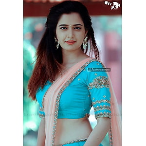 Ashika Ranganath in a turquoise embroidered blouse and peach sari with traditional jewelry HD phone wallpaper