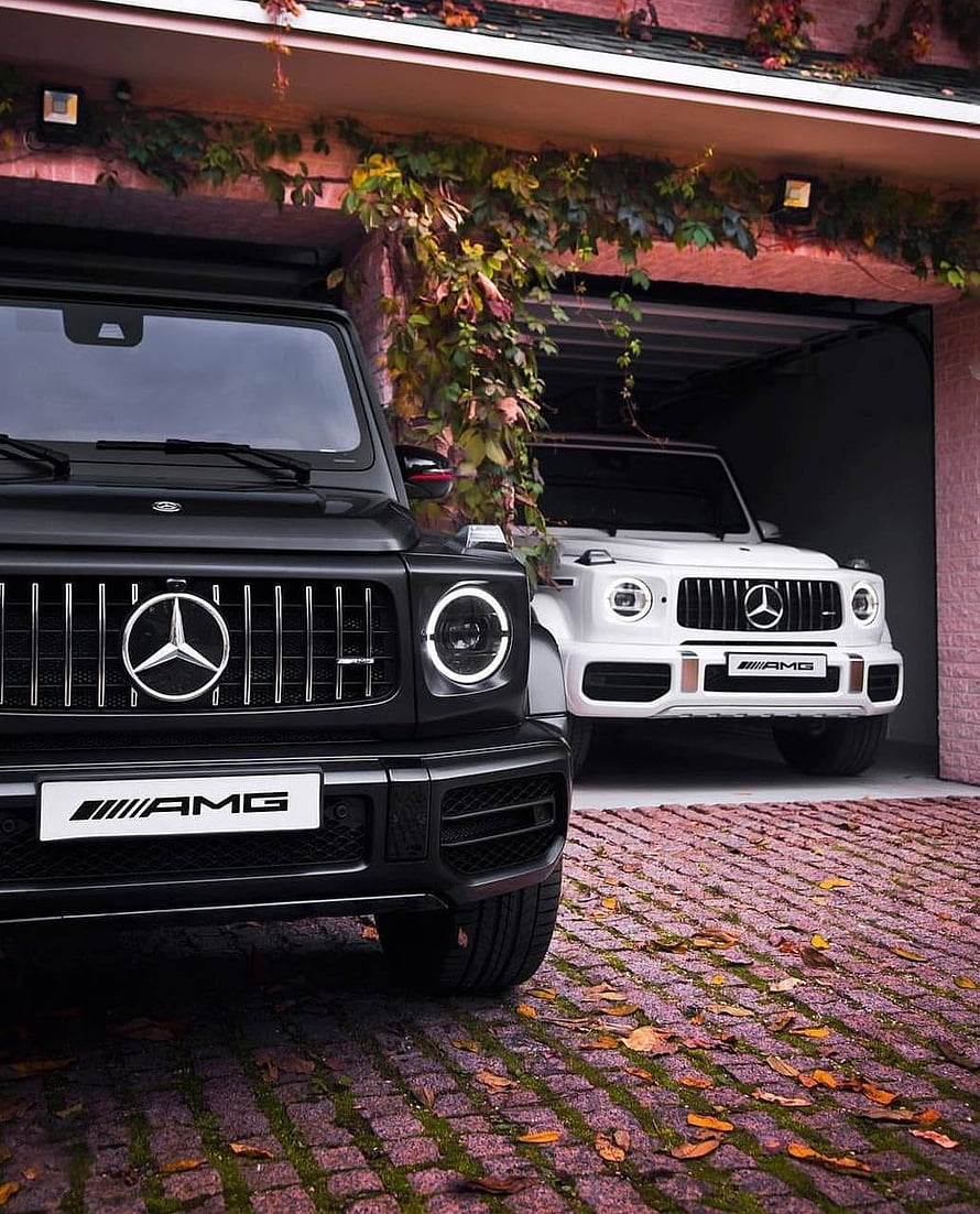 Black and White Mercedes AMG G63 SUVs Parked in a Cobblestone Garage HD phone wallpaper
