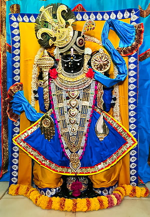 Ornate Black Idol of Lord Krishna Adorned with Gold Jewelry and Blue Silk Garments HD phone wallpaper