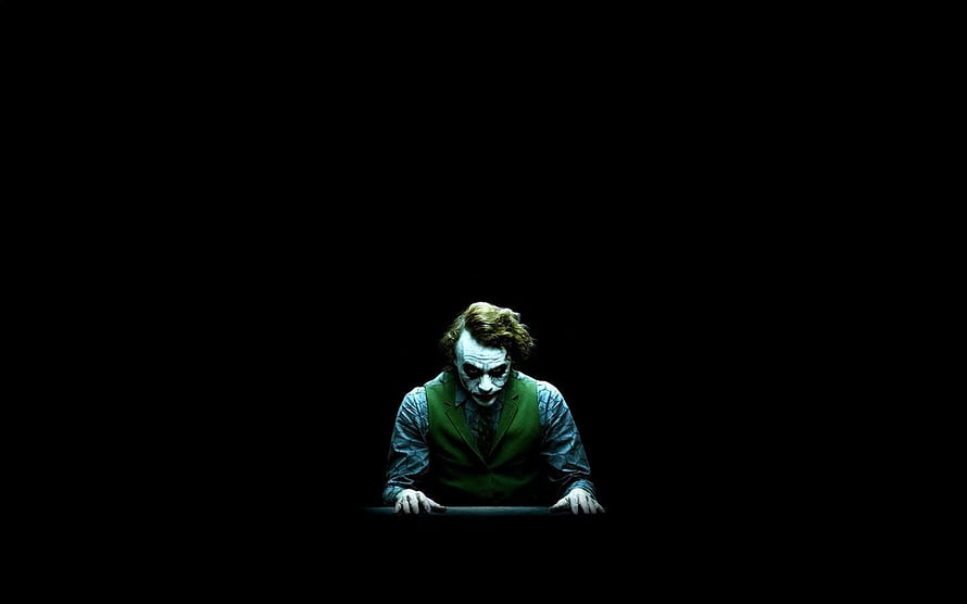 Joker Character in Green Vest Leaning Forward Against Pitch Black Background HD wallpaper