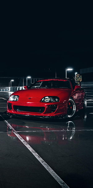 Red Toyota Supra MK4 parked on wet asphalt at night with streetlights reflecting on the glossy surface HD phone wallpaper