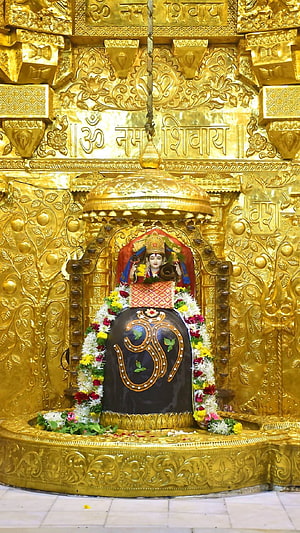 Golden Shiva Lingam Temple Altar with Om Symbol and Floral Garlands HD phone wallpaper