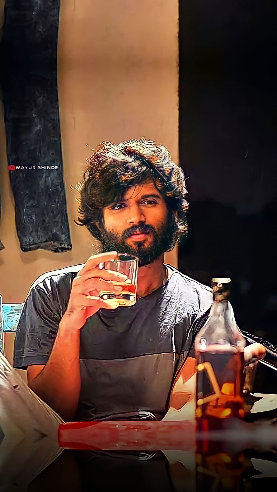 Dhanush in a moody portrait holding a glass of whiskey with a bottle nearby, intense gaze and rugged beard HD phone wallpaper