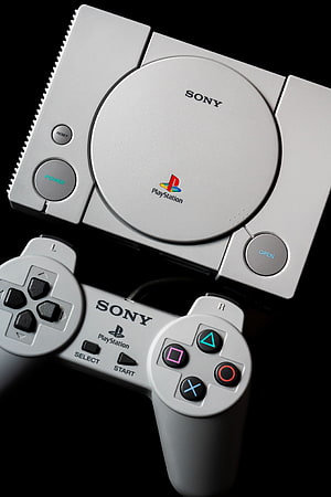 Classic Sony PlayStation 1 Console and Controller on Black Background HD phone wallpaper
