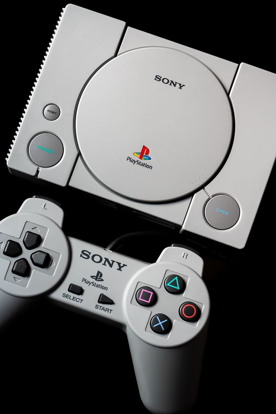 Classic Sony PlayStation 1 Console and Controller on Black Background HD phone wallpaper