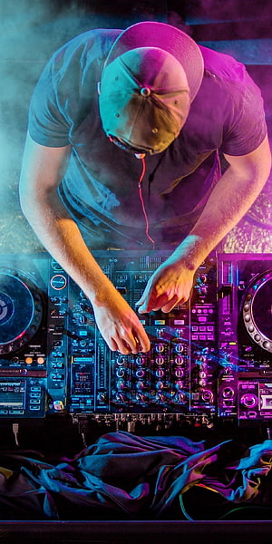 DJ Mixing on a Professional Controller Under Neon Stage Lighting HD phone wallpaper