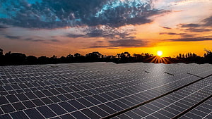 Vast Solar Farm Array Under a Dramatic Sunset Sky with Golden Sunlight and Clouds HD wallpaper