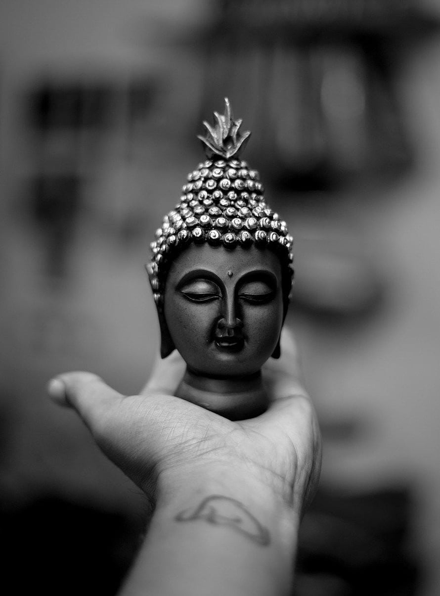 Black and White Photograph of a Buddha Head Statue Held in an Open Palm HD phone wallpaper