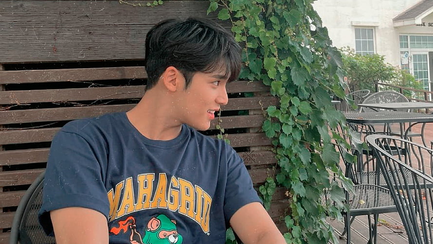 Young man with dark hair wearing a navy graphic t-shirt sitting outdoors at a cafe patio, Kpop Locks, Mingyu Seventeen HD wallpaper