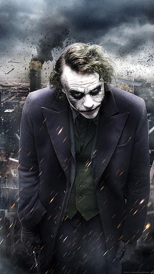 The Joker from The Dark Knight Rises standing before a burning cityscape with falling embers and smoke HD phone wallpaper