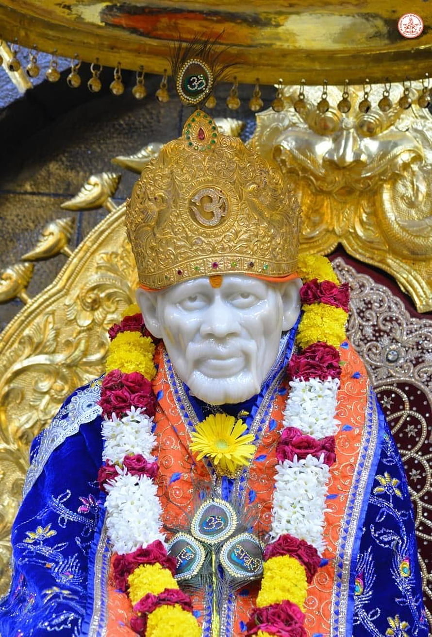 Sai Baba statue adorned with vibrant flower garlands and ornate golden crown HD phone wallpaper