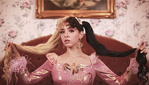 Melanie Martinez in a pink metallic dress holding dual-toned pigtails in a vintage floral room HD wallpaper