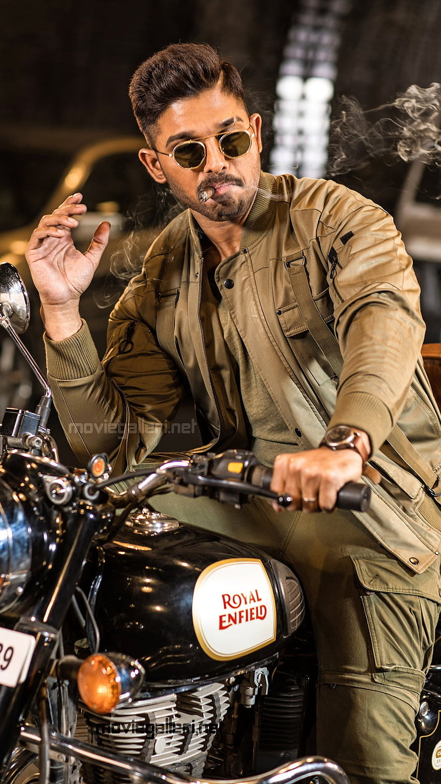 Allu Arjun posing on a Royal Enfield motorcycle wearing a green bomber jacket and sunglasses HD phone wallpaper