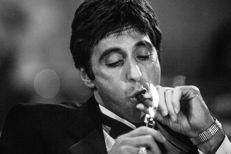 Tony Montana from Scarface lighting a cigar in a black and white portrait HD wallpaper