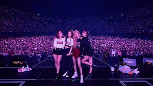 Blackpink Members Posing on Stage During a Massive Stadium Concert with Glowing Audience HD wallpaper