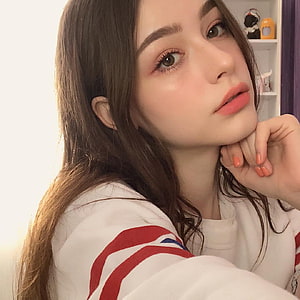 Portrait of a young woman with long brown hair wearing a white sweatshirt with red stripes, posing with hand on chin, Dasha Taran. Hot Nude Porn Pic Gallery HD phone wallpaper