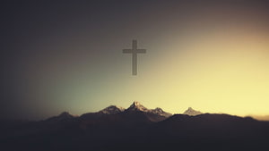 Silhouette of a Christian Cross Floating Above Snow-Capped Mountain Peaks at Sunset HD wallpaper