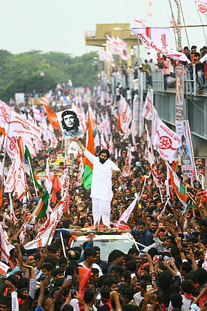 Pawan Kalyan standing on a car holding a Che Guevara portrait during a massive political rally with crowds and flags HD phone wallpaper