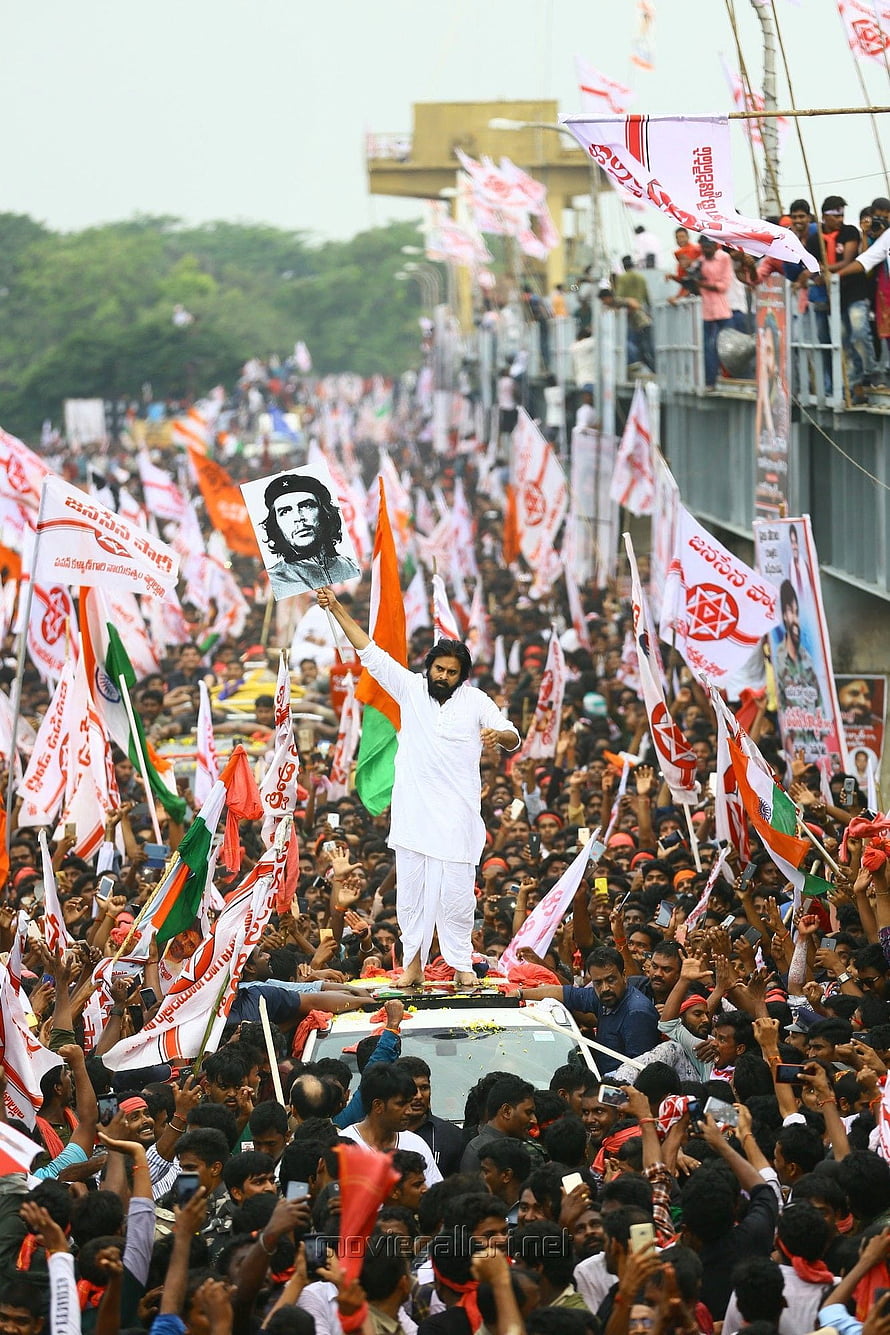 Pawan Kalyan standing on a car holding a Che Guevara portrait during a massive political rally with crowds and flags HD phone wallpaper