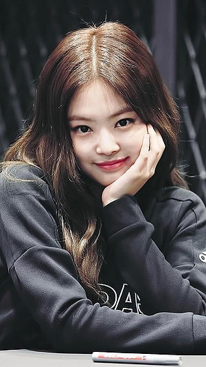 Jennie Kim from Blackpink smiling portrait wearing a black hoodie with hand on cheek HD phone wallpaper