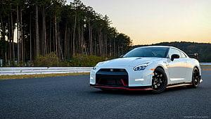 White Nissan GT-R Nismo on a racetrack at sunset with forest background HD wallpaper