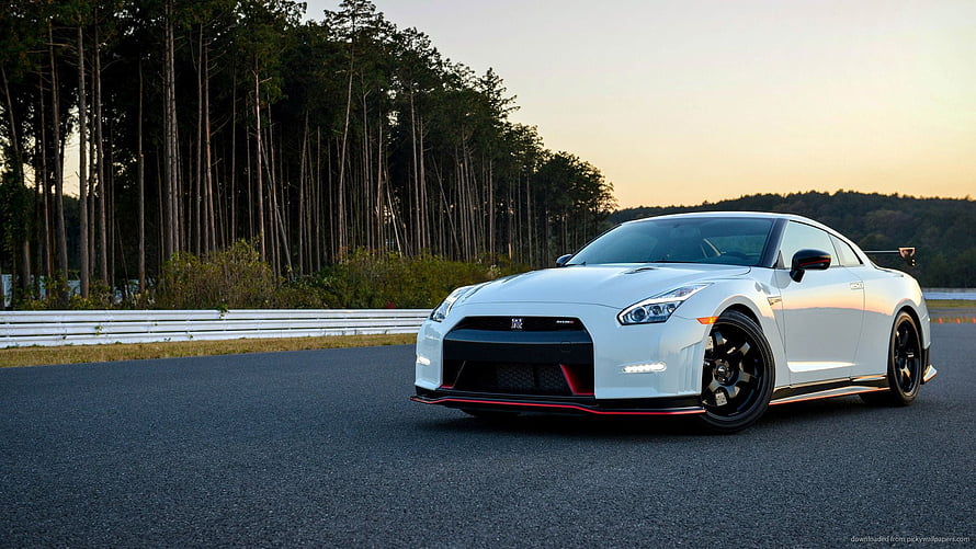 White Nissan GT-R Nismo on a racetrack at sunset with forest background HD wallpaper