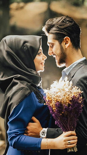 Muslim couple embracing with dried flowers in warm outdoor light HD phone wallpaper