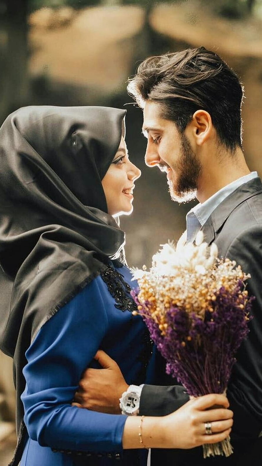 Muslim couple embracing with dried flowers in warm outdoor light HD phone wallpaper