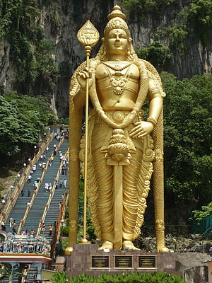 Giant Golden Lord Murugan Statue at Batu Caves with Limestone Cliffs and Staircase HD phone wallpaper