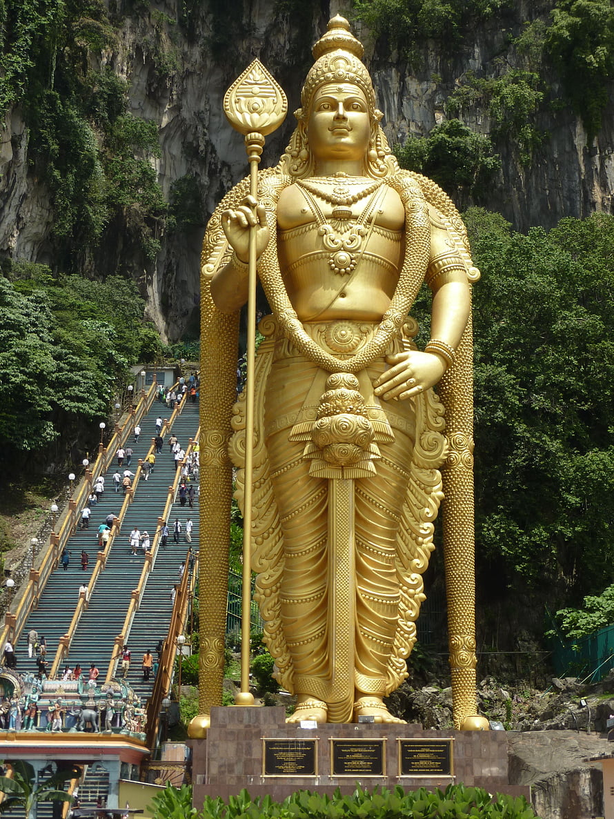 Giant Golden Lord Murugan Statue at Batu Caves with Limestone Cliffs and Staircase HD phone wallpaper