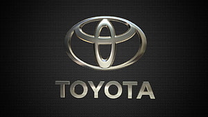 Sleek Metallic Toyota Emblem on Dark Carbon Fiber Texture HD wallpaper