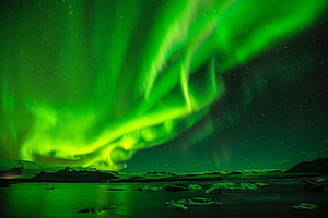 Vibrant Green Aurora Borealis Dancing Over a Starry Night Sky and Snowy Landscape HD wallpaper