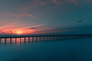 Serene Sunset Over Ocean With Long Wooden Pier Silhouette HD wallpaper