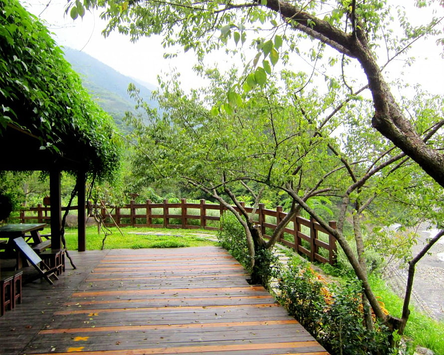 Rustic wooden deck overlooking a lush green garden with a mountain backdrop HD wallpaper