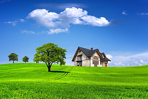 Modern Stone House on a Lush Green Hill with Blue Sky and Fluffy Clouds HD wallpaper