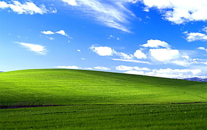 Rolling Green Hills Under a Bright Blue Sky with Scattered White Clouds HD wallpaper