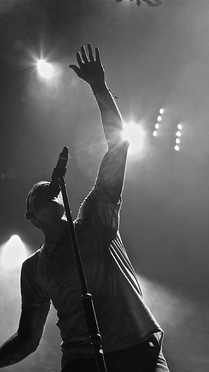 Chester Bennington Silhouette Performing on Stage with Raised Arm and Microphone HD phone wallpaper