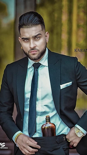 Karan Aujla in a black suit with a whiskey bottle tucked into his waistband HD phone wallpaper