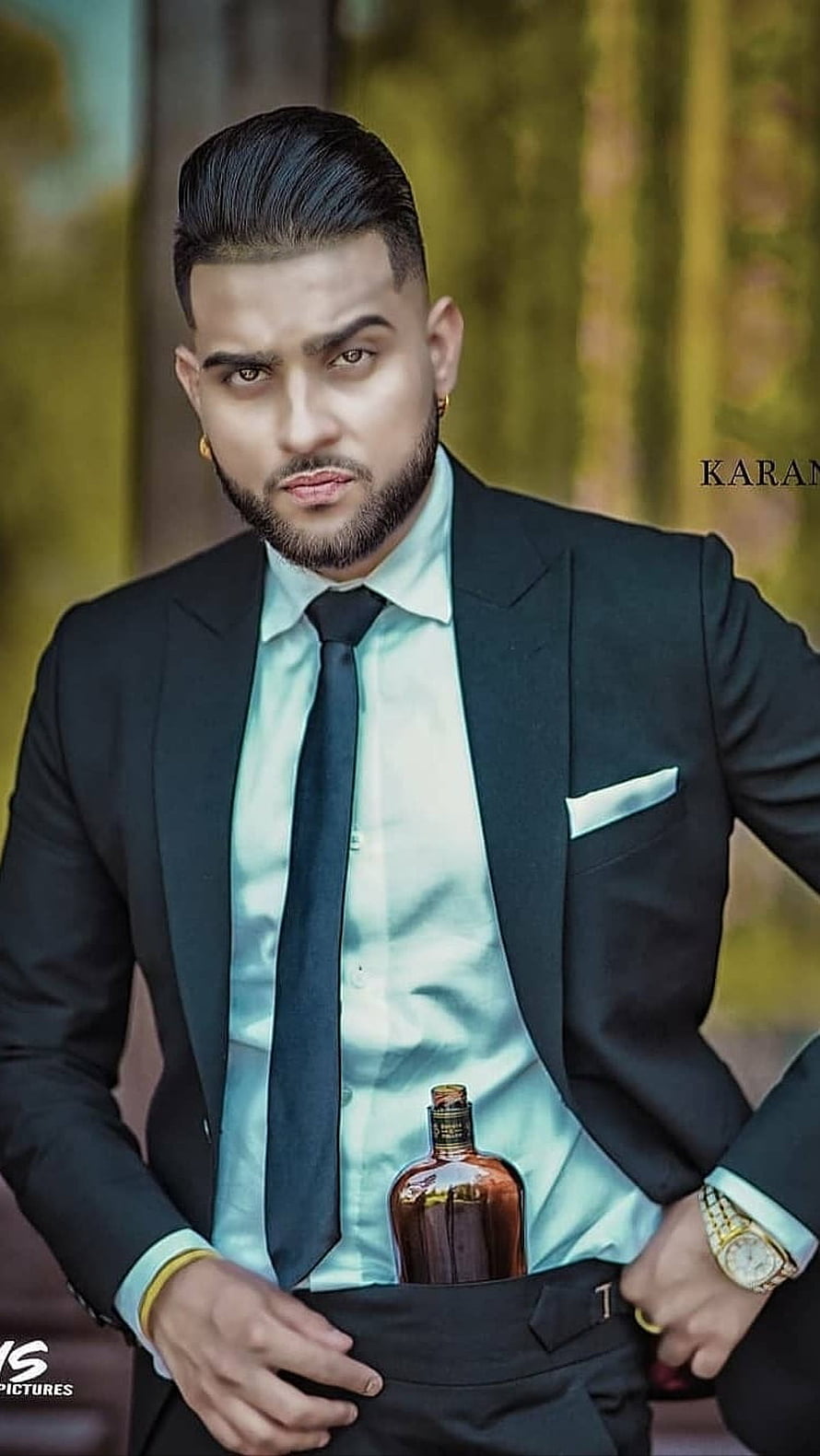 Karan Aujla in a black suit with a whiskey bottle tucked into his waistband HD phone wallpaper