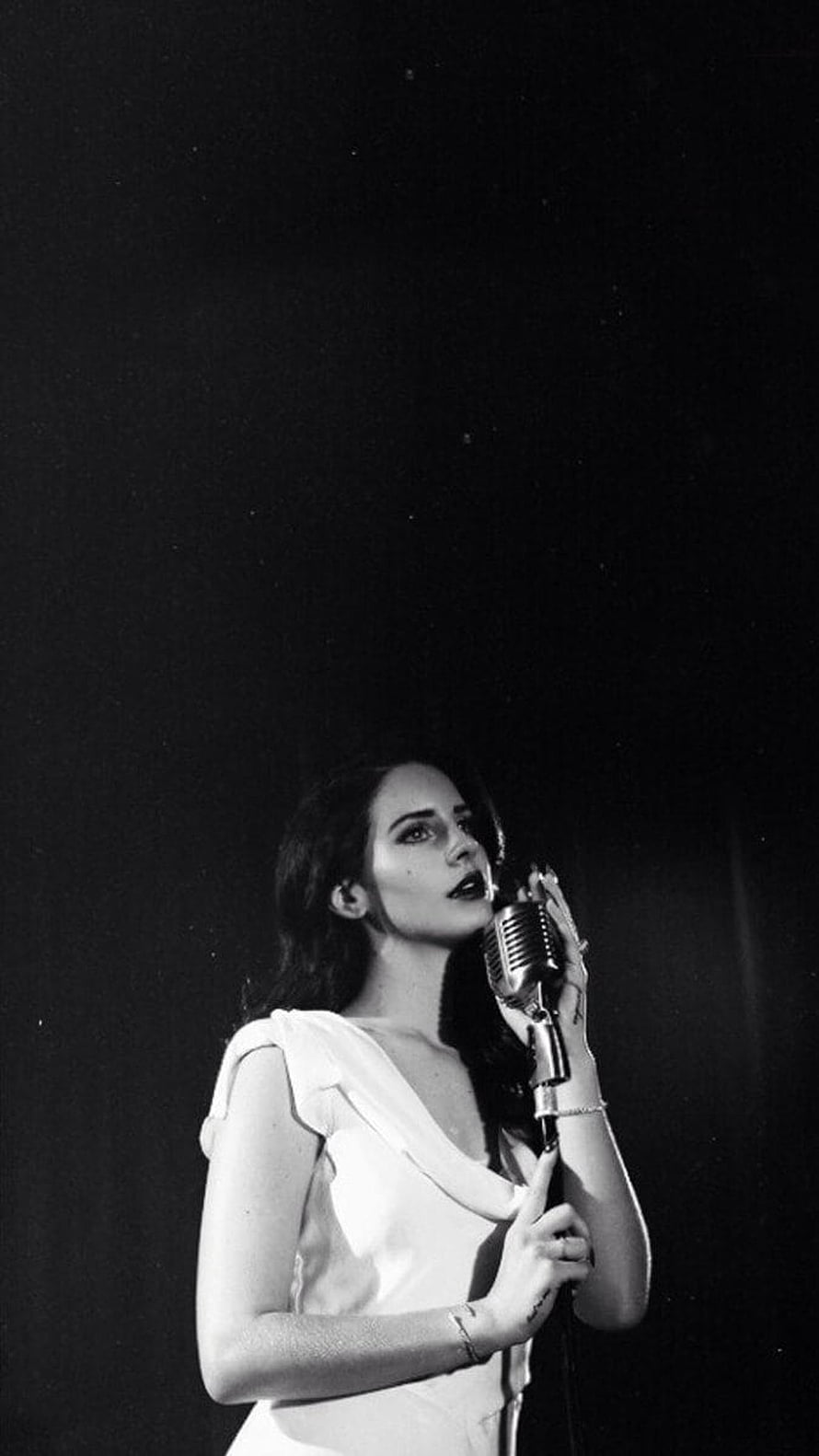 Lana Del Rey performing with vintage microphone in dramatic black and white portrait HD phone wallpaper
