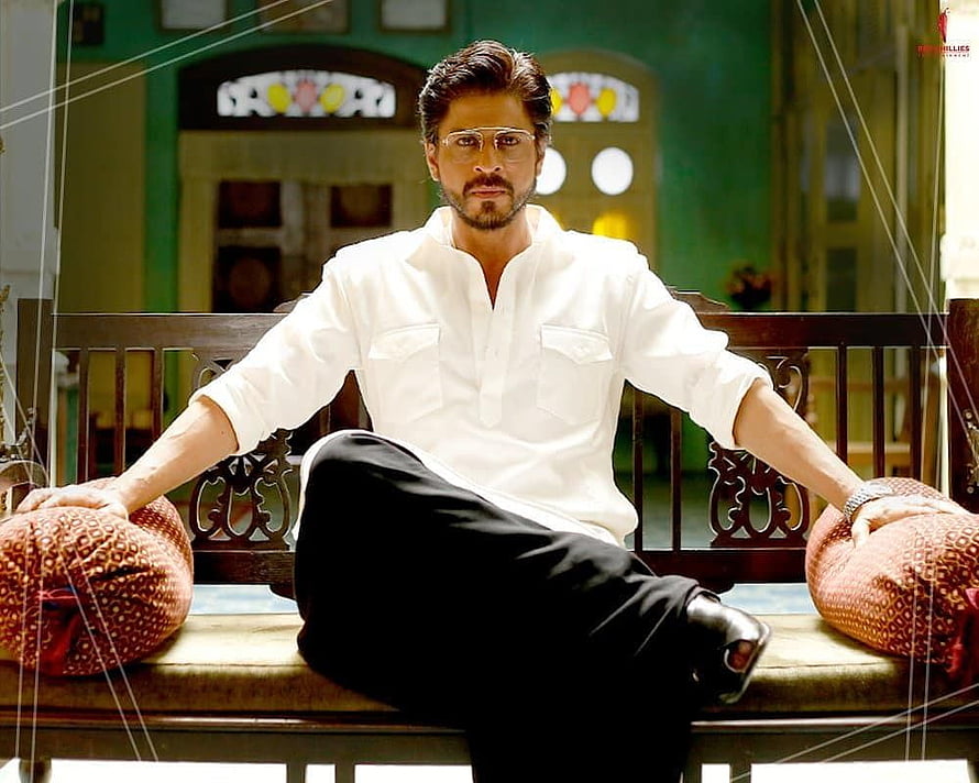 Shah Rukh Khan as Raees in White Shirt and Glasses Seated on Wooden Bench HD wallpaper