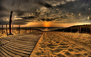 Dramatic Golden Hour Beach Scene With Wooden Boardwalk Leading To Ocean Horizon HD wallpaper