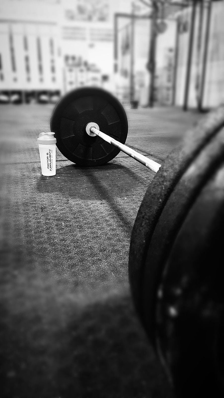 Black and white barbell and shaker bottle on gym floor HD phone wallpaper