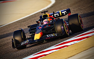 Red Bull Racing Formula 1 car speeding around a track corner with red and white curbs HD wallpaper