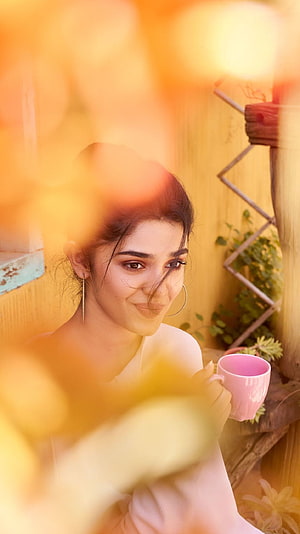Kriti Shetty Holding a Pink Mug in a Warm Sunlit Garden Setting HD phone wallpaper