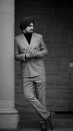 Sidhu Moose Wala in a double-breasted suit and turban leaning against a stone column in black and white HD phone wallpaper
