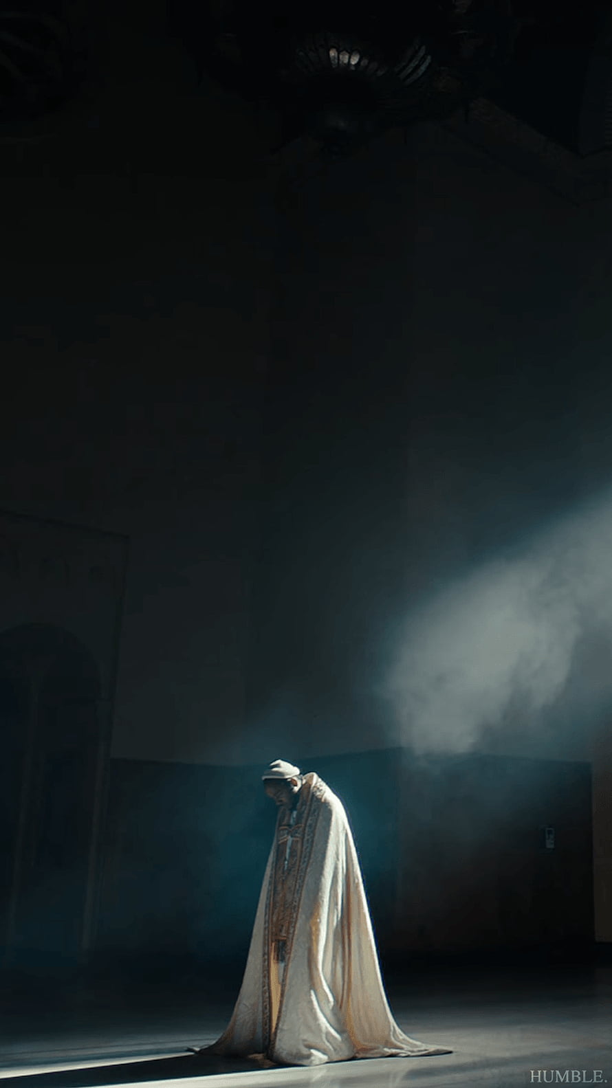 Kendrick Lamar in White Robe Under Dramatic Light Beam in Dark Cathedral Interior HD phone wallpaper