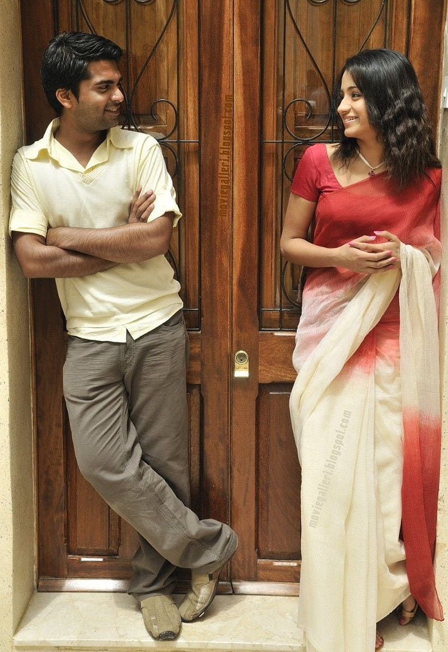 Vinnaithandi Varuvaya movie still of a smiling couple standing by a wooden door HD phone wallpaper