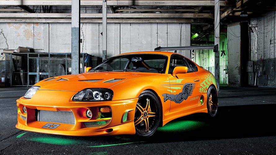 Orange Toyota Supra MK4 with Custom Graphics and Neon Underglow in Industrial Garage HD wallpaper